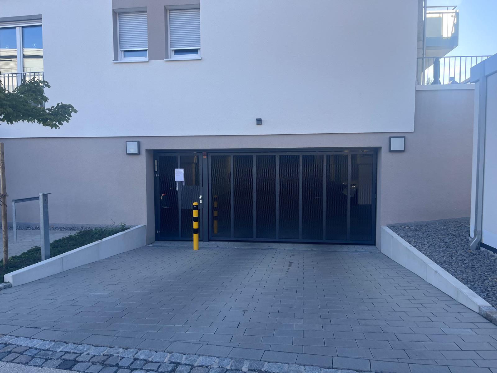 Verglastes Falttor als Tiefgarageneinfahrt